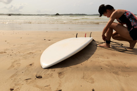 young woman surfer ready to surf on a beachの写真素材