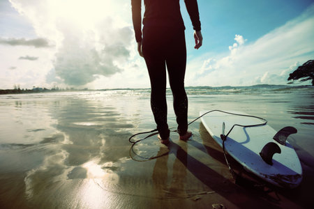 young woman surfer ready to surf on a beach