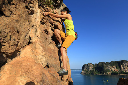 young woman rock climber climbing at seaside cliffの写真素材