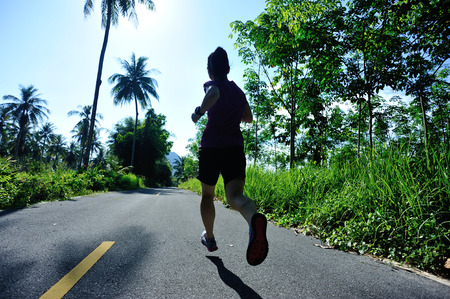 healthy lifestyle woman runner running on morning tropical forest trailの写真素材