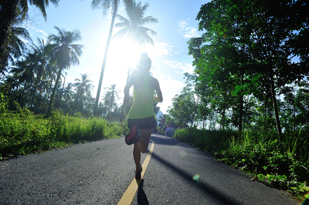 healthy lifestyle woman runner running on morning tropical forest trailの写真素材