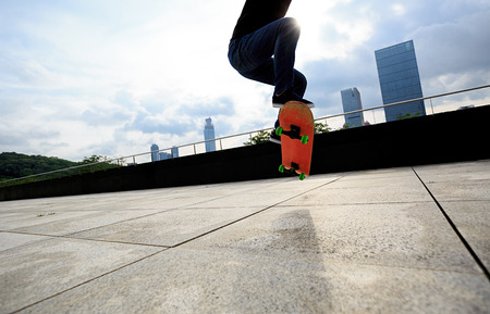 young woman skateboarder skateboarding at cityの写真素材
