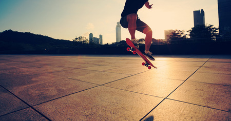 young woman skateboarder skateboarding at cityの写真素材