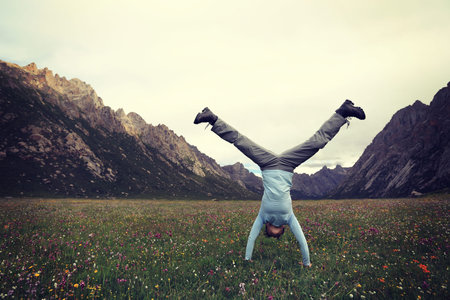 woman doing a handstand on mountain meadow