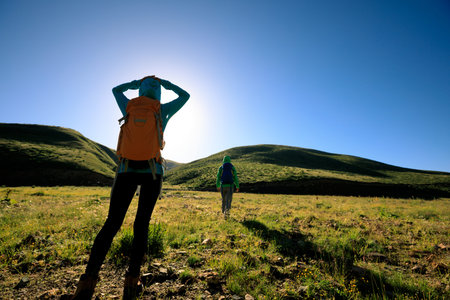 two backpacking women hiking in sunrise mountains