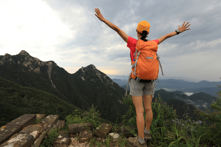 successful woman hiker open arms on the top of mountainの写真素材