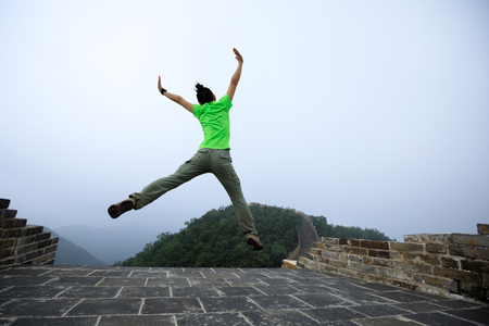 successful woman hiker jumping on great wallの写真素材