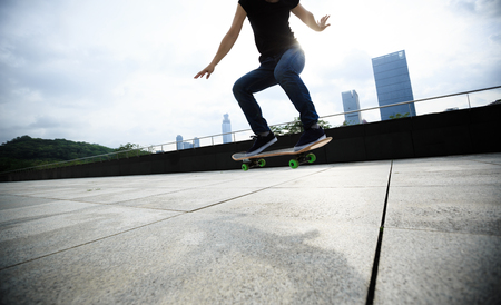 Woman skateboarder skateboarding at sunrise cityの写真素材
