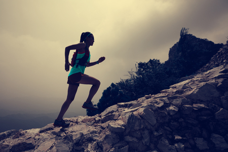 woman trail runner running on the great wall top of mountainの写真素材