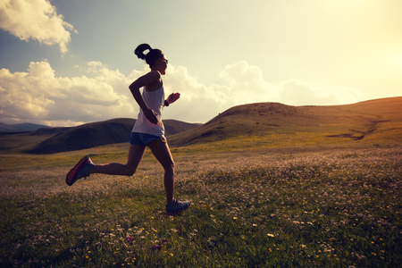 young fitness woman runner running on grassland trailの写真素材