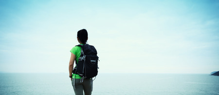 woman backpacker enjoy the view on seaside mountain top cliffの写真素材