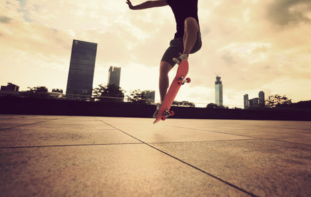 young woman skateboarder skateboarding at sunrise city