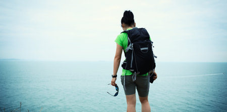 woman backpacker enjoy the view on seaside mountain top cliff