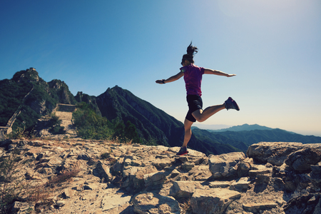woman trail runner running at great wall on the top of mountainの写真素材