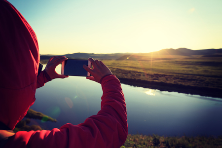 taking photo with smart phone in beautiful sunset landscapeの写真素材