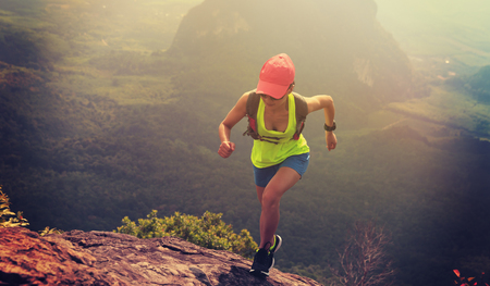 Young fitness woman trail runner running up to  mountain topの写真素材