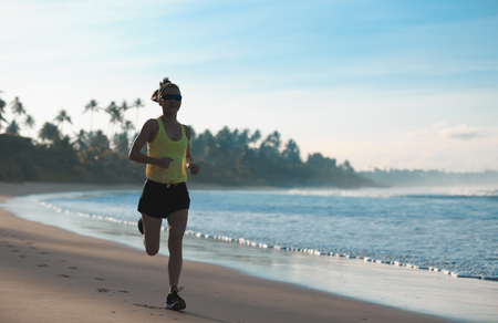 young fitness woman runner running on sandy beachの写真素材