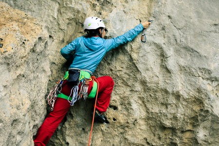 female rock climber climbing on mountain cliff