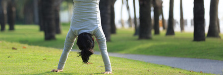 Young woman practice handstand on park meadowの写真素材