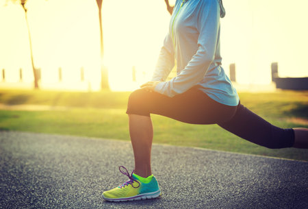 Young fitness woman stretching legs before run at tropical park