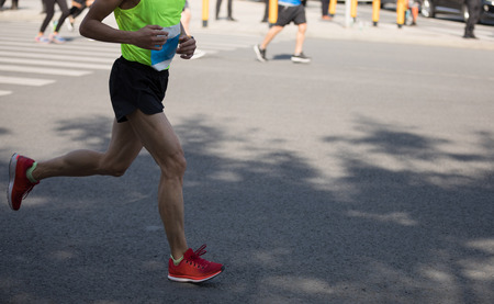 marathon runner legs running on city roadの写真素材