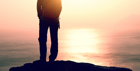 female hiker stand on the cliff edge at sunrise seasideの写真素材