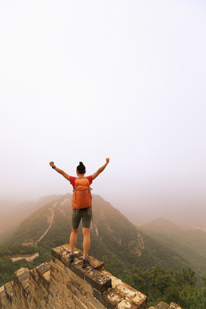 successful female hiker open arms to the great wall on the top of mountainの写真素材