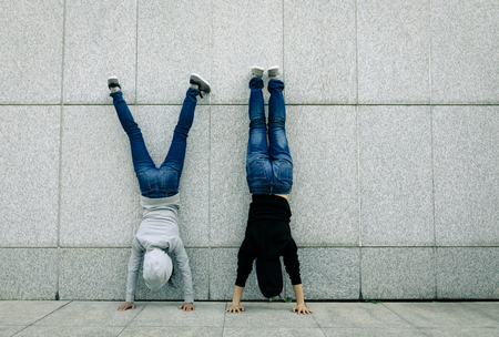 Two female hipster doing handstand against wall in cityの写真素材