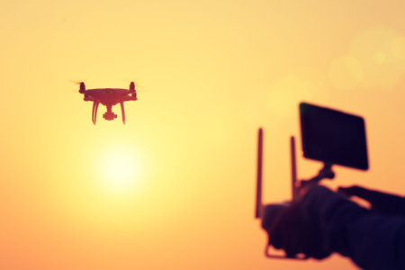 silhouette of remote control a flying drone which taking photo over sunrise sea