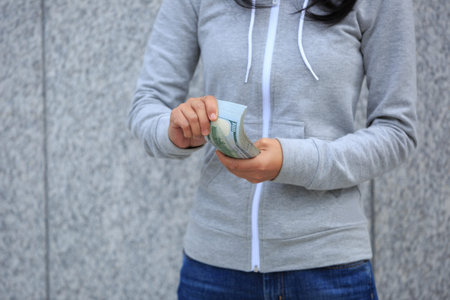 Female hand put money into pocket on blurred city background