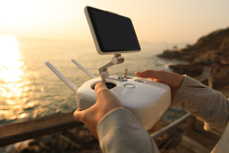 silhouette of remote control a flying drone which taking photo over sunrise sea