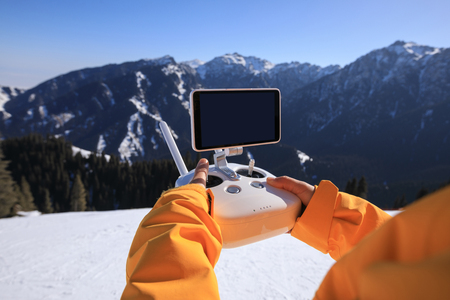remote controlling a flying drone on winter mountain topの写真素材