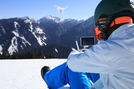 remote controlling a flying drone on winter mountain top