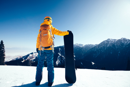 successful snowboarder with snowboard on winter mountain topの写真素材
