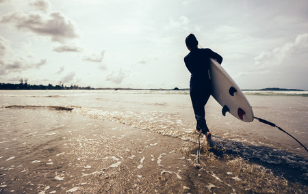woman surfer with surfboard running on beachの写真素材