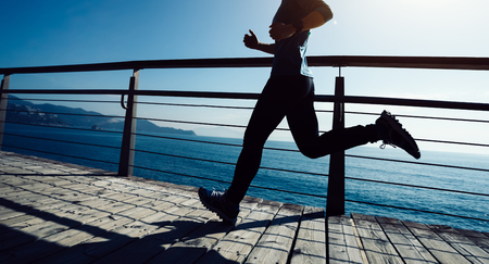 Sporty female runner running on seaside boardwalk の写真素材