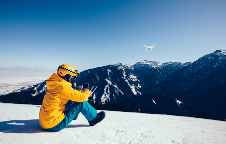 remote controlling a flying drone on winter mountain topの写真素材