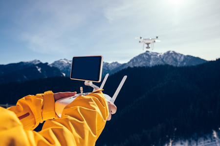 remote controlling a flying drone on winter mountain topの写真素材