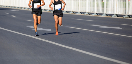 marathon runners legs running on city roadの写真素材