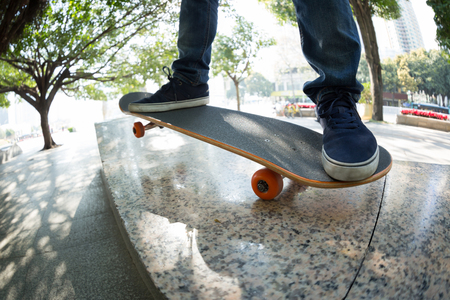 young skateboarder legs riding skateboard at city skateparkの写真素材