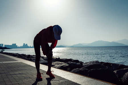 woman runner hold the sports injured knee on sunrise seasideの写真素材