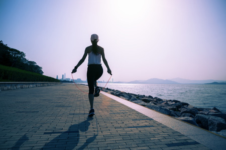 sporty young fitness woman jumping rope on coast trailの写真素材