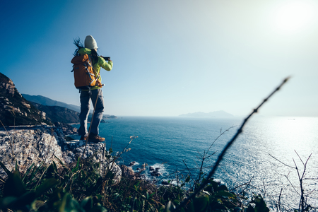 Young Woman Hiker Using Smartphone taking photo at Seasideの写真素材