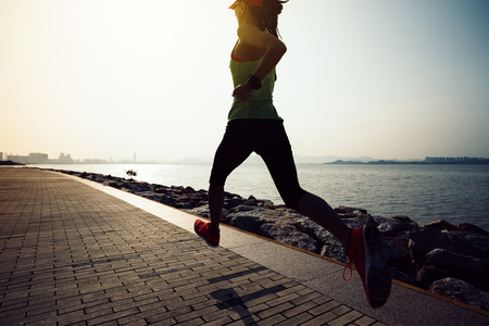 sporty young fitness woman running on sunrise coastの写真素材