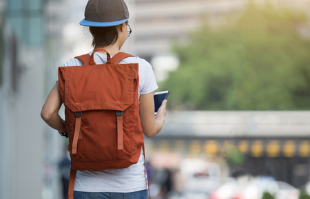 young woman walking with smart phone in modern cityの写真素材