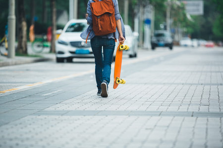 woman walking with sakteboard in hand on city street
