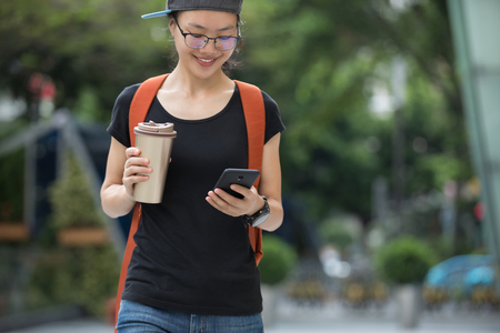 woman walking with a cup of coffee   in hand on city streetの写真素材
