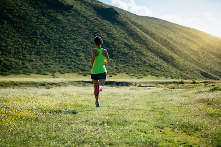 Young woman running on grasslandの写真素材