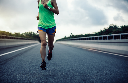 Young fitness woman running on city roadの写真素材
