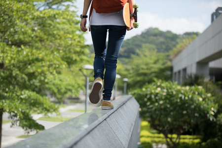 Young woman walking on the edge of a urban building wall at cityの写真素材